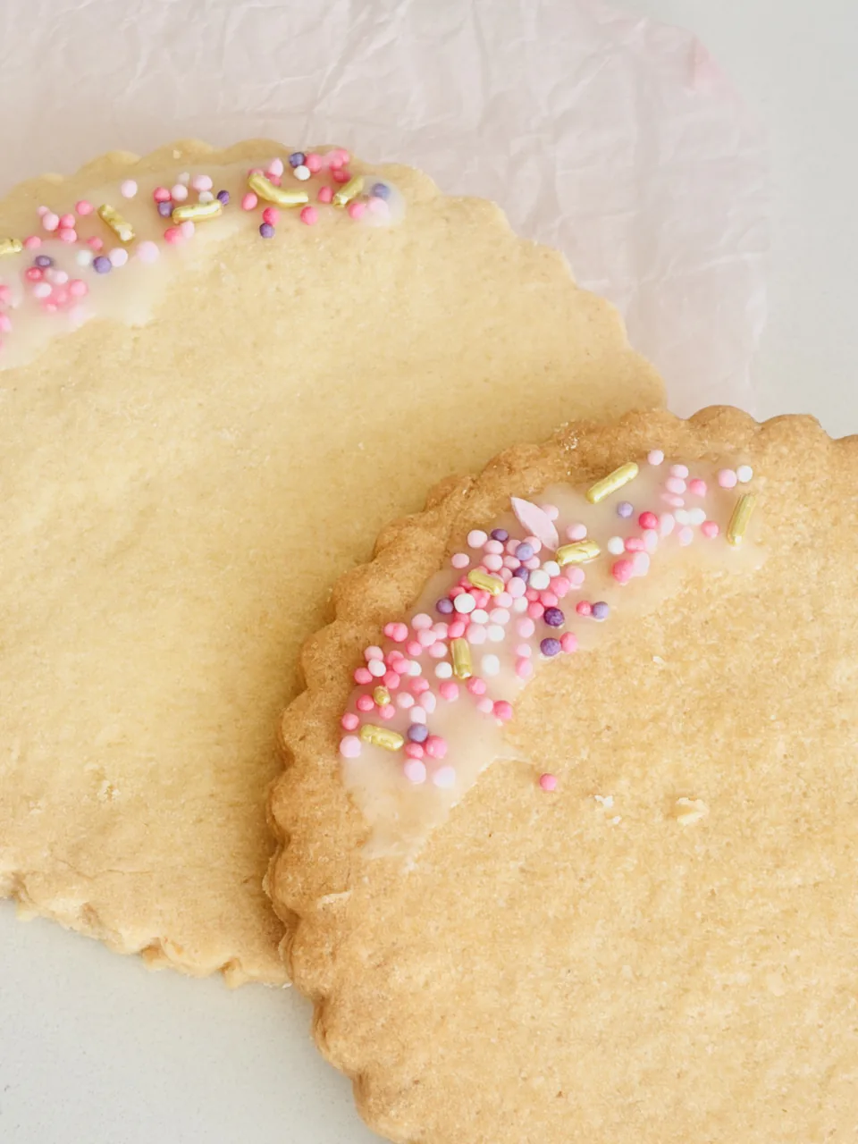 Twee boterkoekjes met roze, paarse en gouden sprinkles